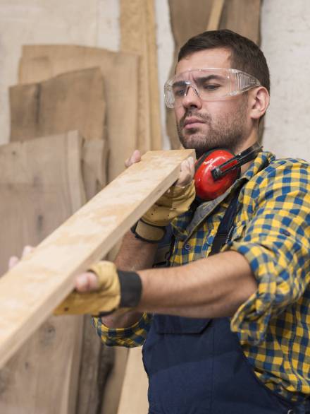 male-carpenter-seriously-looking-wooden-plank